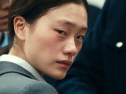 Junge japanische Frau schaut ernst in die Kamera, Szene aus dem Film DECEMBER